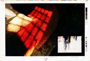 Descrição da imagem: Imagem colorida e horizontal. Na parte central e à esquerda, há uma grande mancha vermelha, com textura quadriculada, que ocupa boa parte da imagem. Na parte inferior à direita, em tamanho reduzido, há a fotografia desbotada de pessoas caminhando na rua. No entorno, uma borda branca com marcas de cores ciano, magenta, amarelo e preto. No canto inferior direito, há uma assinatura na cor vermelha. Fim da descrição da imagem.