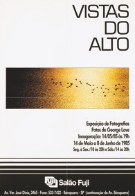 Descrição da imagem: Cartaz vertical da exposição "Vistas do Alto" com fundo branco e borda inferior preta. Na parte superior, está escrito "Vistas do Alto" em letras maiúsculas pretas, alinhadas à direita. Abaixo do texto, há uma fotografia aérea retangular horizontal com um degradê de cores do por do sol refletido nas águas de um rio, do preto à esquerda para o amarelo à direita, com várias aves voando em formação no centro da imagem. Na parte inferior do cartaz, há informações sobre uma exposição de fotografias: "Exposição de Fotografias Fotos de George Love Inauguração: 14/05/85 às 19h 14 de Maio a 8 de Junho de 1985 Seg. à Sex./10 às 20h e Sab./14 às 20h" em letras pretas menores. Na base preta do cartaz, há o logo do Salão Fuji e a informação de endereço e telefone em letras brancas. Fim da descrição da imagem.