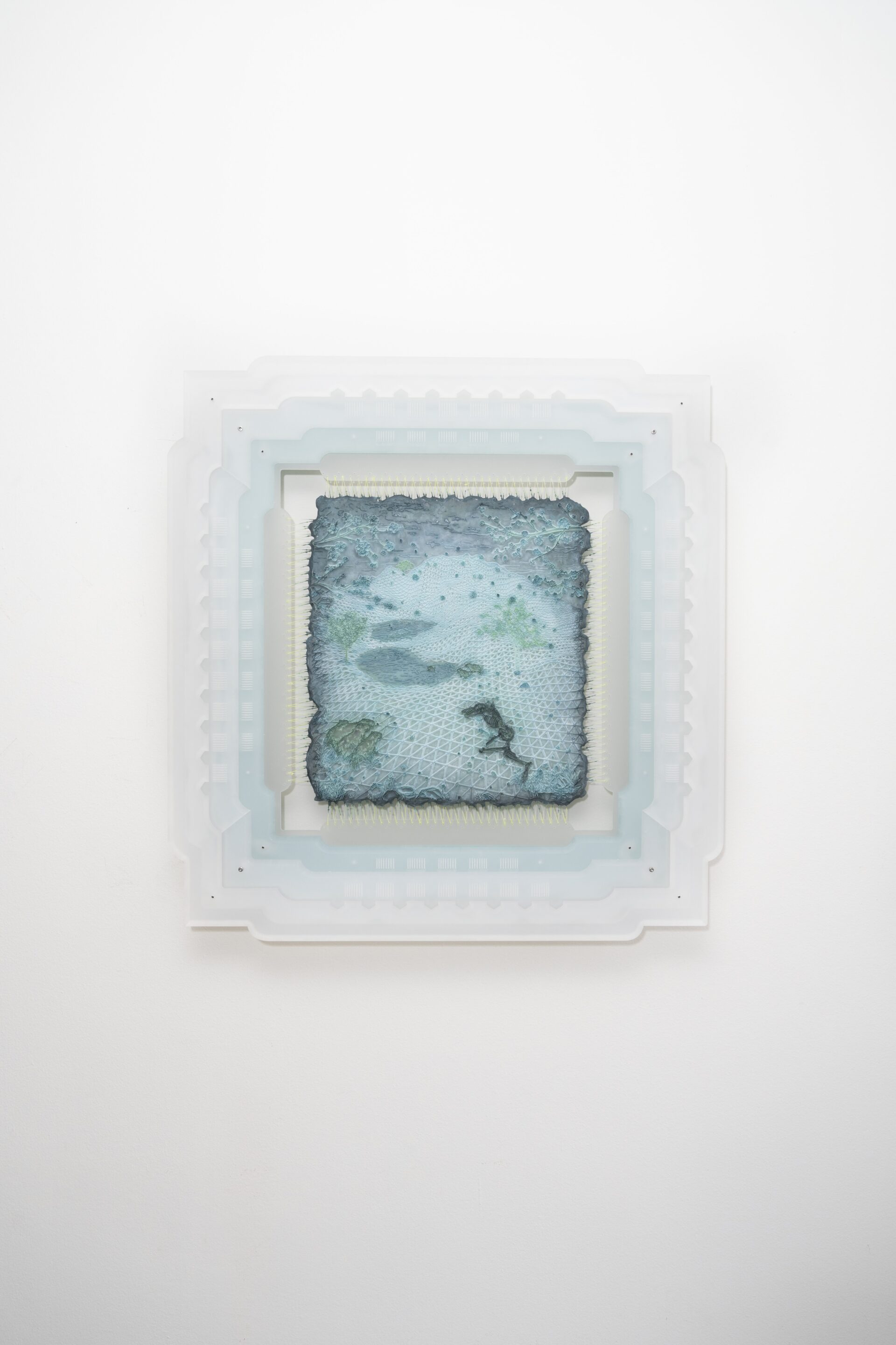 Descrição da imagem: fotografia horizontal de um desenho em impressão 3D em tons de azul e verde. Na parte superior, alguns galhos e folhagens. Ao centro, tramas de fios em uma superfície, com espaçamentos entre as linhas que vão se estreitando até se transformarem em montanhas ao fundo. Na parte inferior, uma forma escura, com tronco e duas pernas finas, que se assemelha a um humanóide. O desenho está costurado por diversas linhas em uma moldura feita de camadas sobrepostas em tons claros de azul e branco. Fim da descrição da imagem.