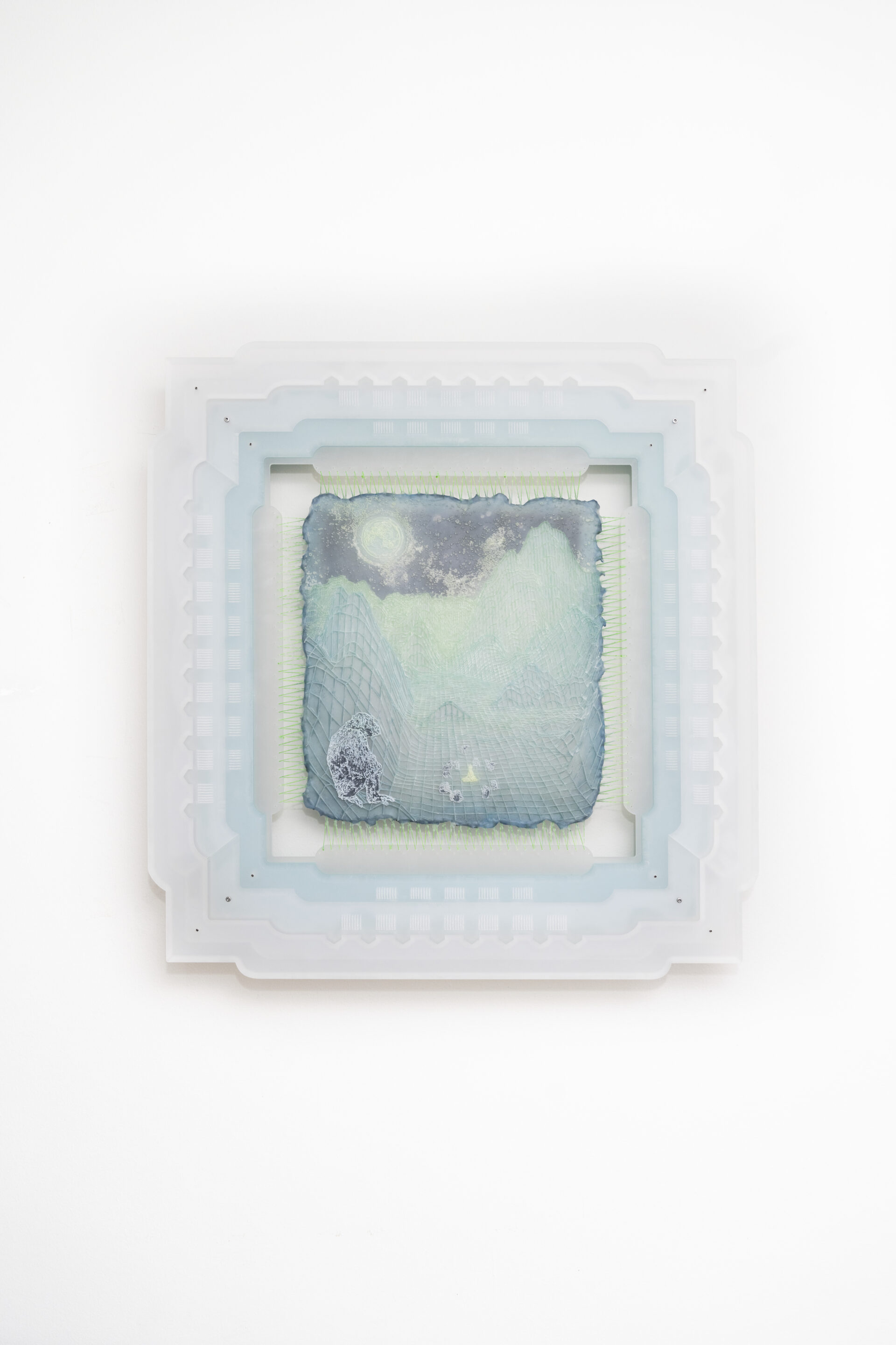 Descrição da imagem: Fotografia horizontal de um desenho em impressão 3D em tons de azul e verde. Na parte superior, um céu azul escuro com uma lua verde azulada. À esquerda, na parte inferior, um chimpanzé em tons de azul, está sentado. Ao centro, a chama de uma fogueira em tramas de fios se expande pelas laterais e ao fundo, criando montanhas em linhas sinuosas. O desenho está costurado por diversas linhas em uma moldura feita de camadas sobrepostas em tons claros de azul e branco. Fim da descrição da imagem.