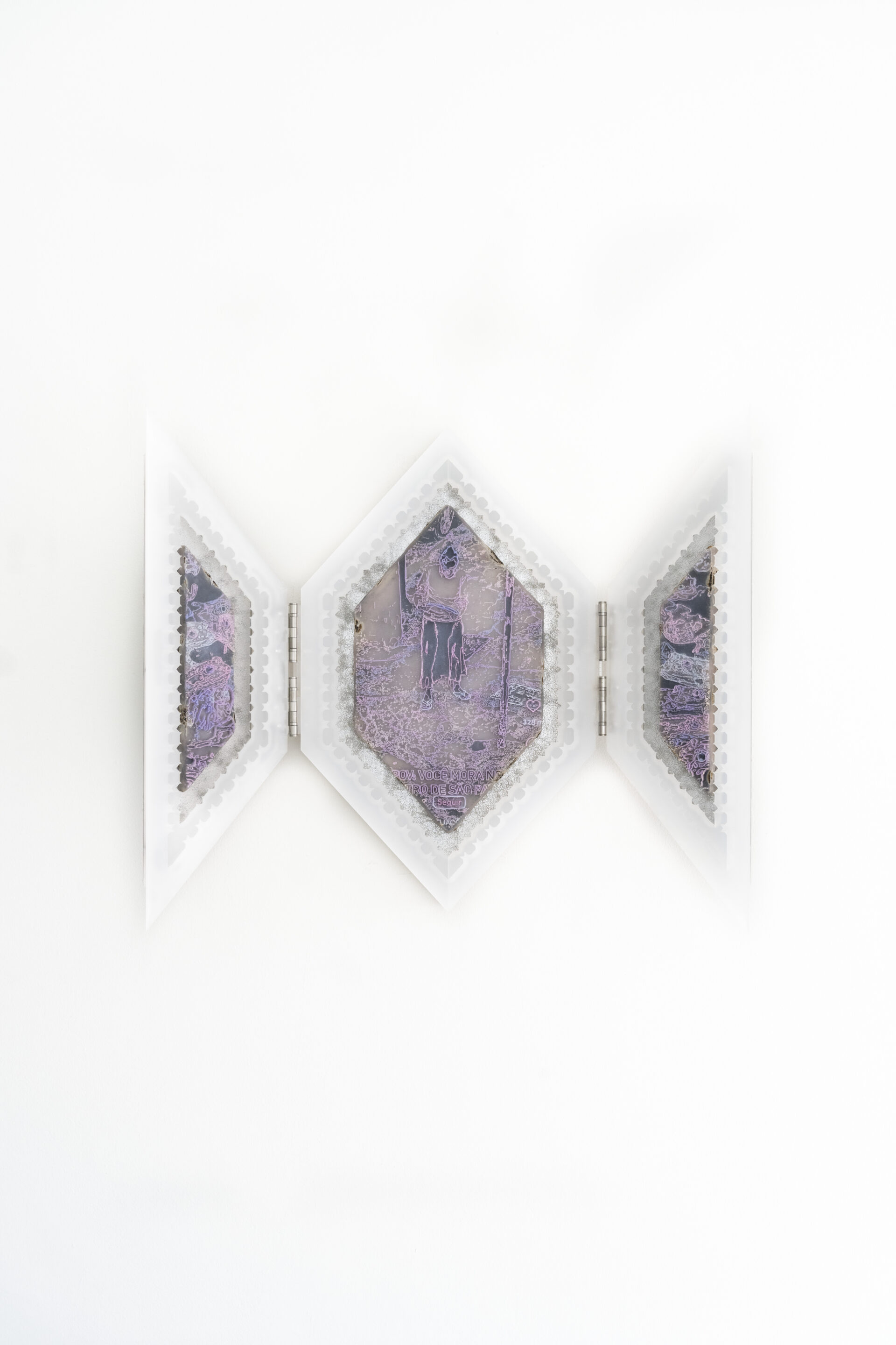 Descrição da imagem: fotografia de objeto hexagonal aberto em três partes. As laterais são pequenas portas de um oratório, em losango, presas por dobradiças. Ao centro, entre as portas, desenho em impressão 3D em tons de rosa, lilás e preto. Em linhas irregulares, uma figura humana em pé. Nas portas outras linhas irregulares, criam formas abstratas. Na parte inferior: “POV: Você mora no centro de São Paulo” e abaixo em formato de ícone está escrito “seguir” também na cor lilás. O objeto é emoldurado por camadas em branco sobrepostas. O fundo é branco. Fim da descrição da imagem.