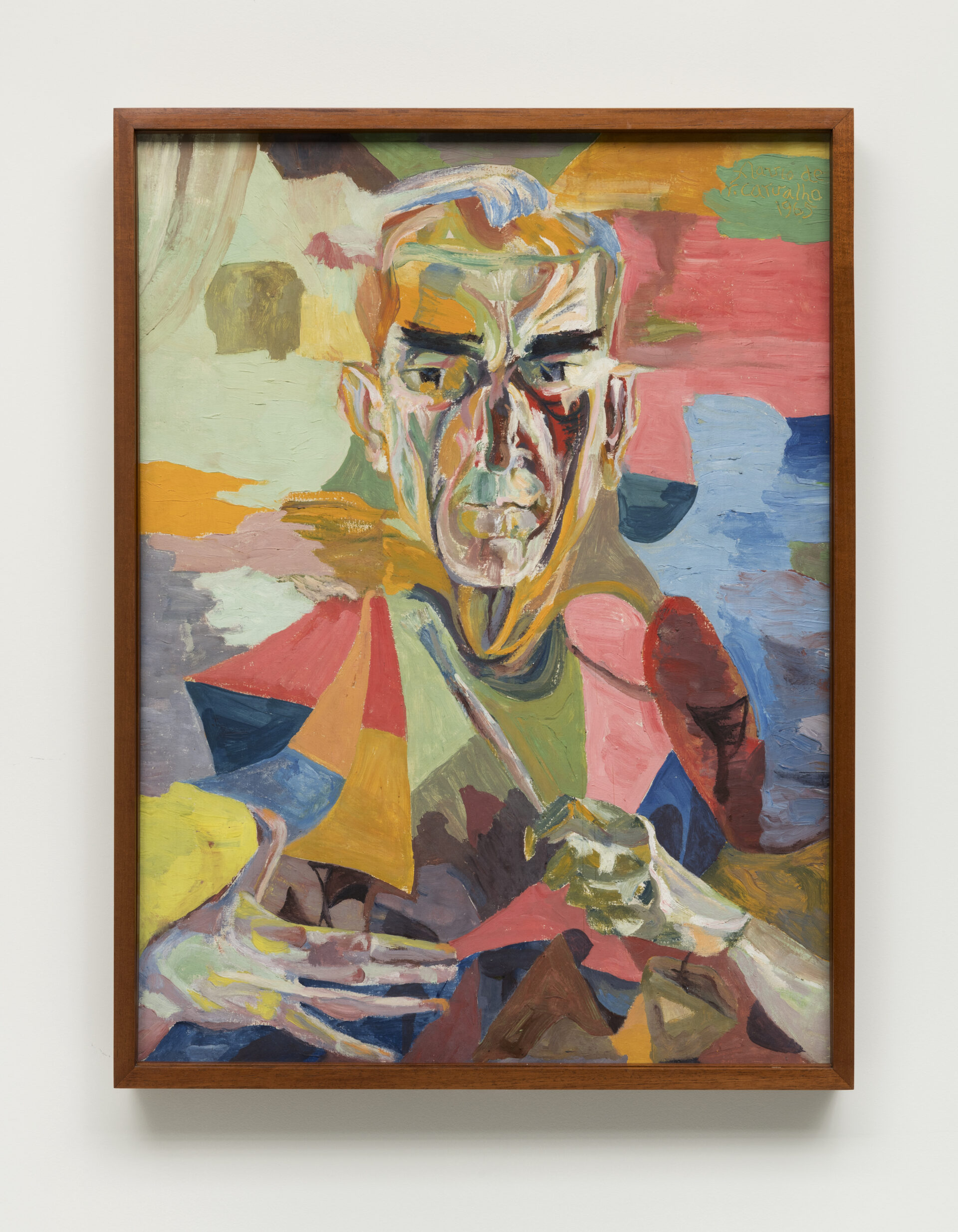 Descrição da imagem: Pintura cubista de um homem visto de frente, do peito para cima. É branco, de cabelo curto e liso branco. As sobrancelhas são grossas e pretas, os olhos também pretos. As mãos estão abertas à frente do peito. A figura e o fundo estão pintados de maneira fragmentada em rosa, verde, amarelo, azul e laranja. A moldura é marrom. Fim da descrição. 