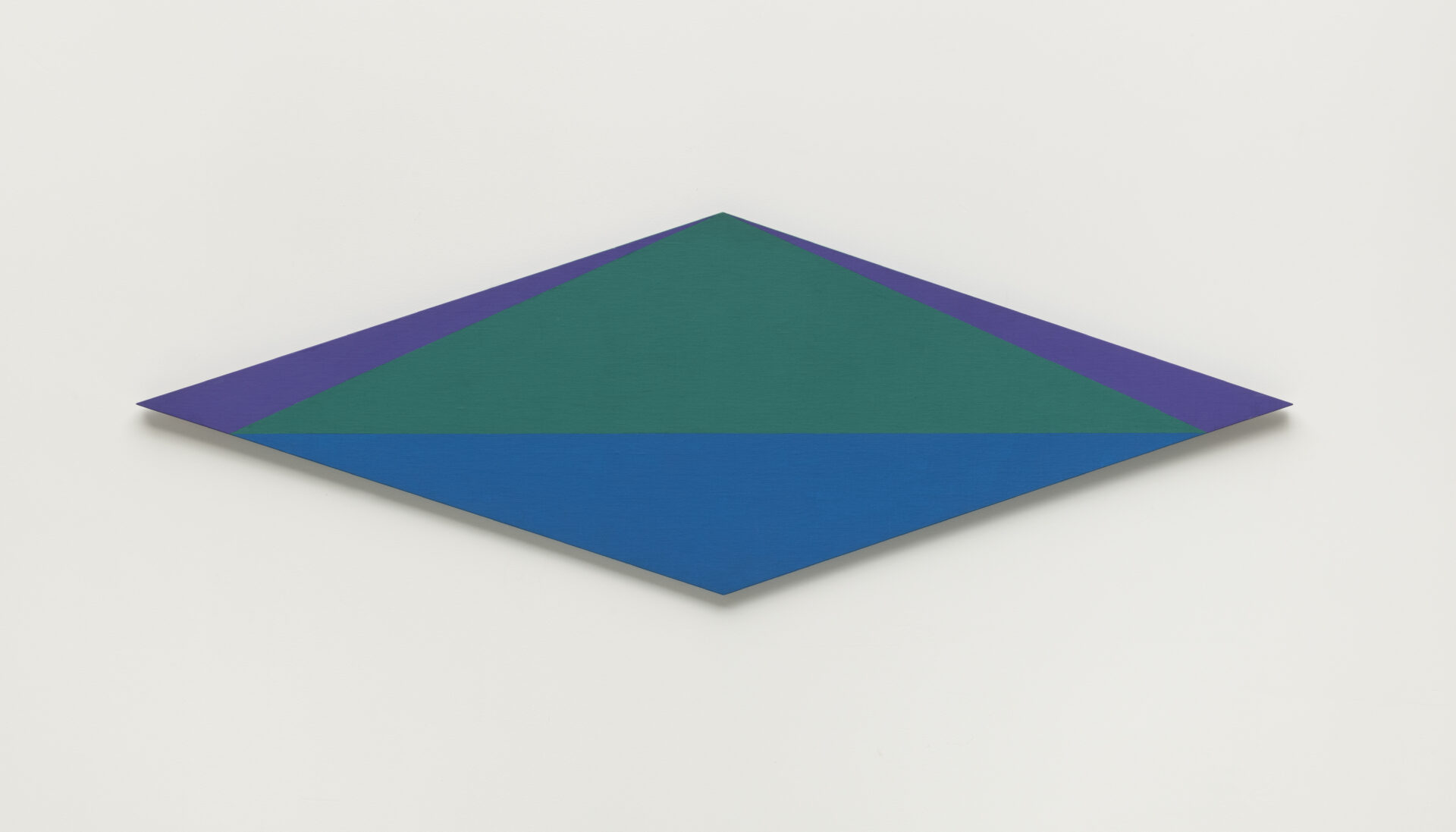 Descrição da imagem: A tela, em formato de losango posicionada na horizontal, apresenta uma pintura geométrica com formas planas e simétricas. Nas extremidades superiores esquerda e direita, há dois triângulos retângulos roxos. Ao centro, um losango menor que o da tela, está dividido horizontalmente: a metade superior é verde, e a inferior azul. Fim da descrição. 

