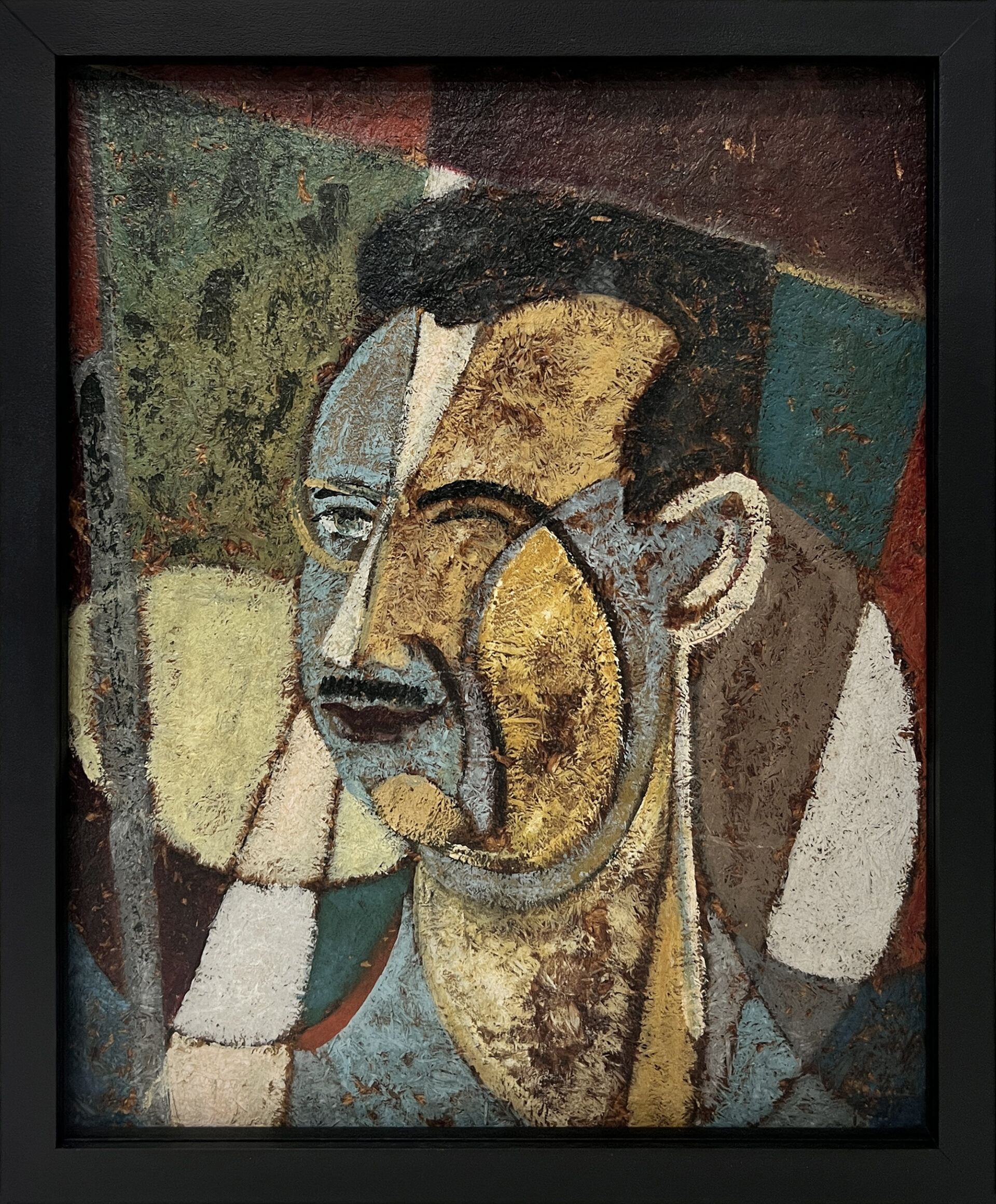 Descrição da imagem: A pintura colorida tem formato retangular vertical e mede aproximadamente cinquenta e três centímetros de altura por quarenta e três centímetros de largura, incluindo a moldura preta fina. O fundo é composto por formas geométricas que se sobrepõem e se fragmentam, cada uma com uma cor distinta, em tons escuros e terrosos, como verde, marrom, cinza e um vermelho amarronzado. No centro, está o busto estilizado de um homem, com o rosto levemente virado para a esquerda, visto de frente.  O cabelo, curto e preto, forma um desenho levemente quadrado na parte superior da cabeça. A orelha direita tem traços simples e está pintada de cinza claro. O rosto é formado por planos sobrepostos, em combinações de ângulos e curvas, com cores que variam entre amarelo, bege, azul, cinza e marrom. À esquerda, a face é azulada. Do centro da testa até parte do nariz, predomina um cinza claro, enquanto do lado direito, aparecem áreas em amarelo e azul. Fim da descrição.