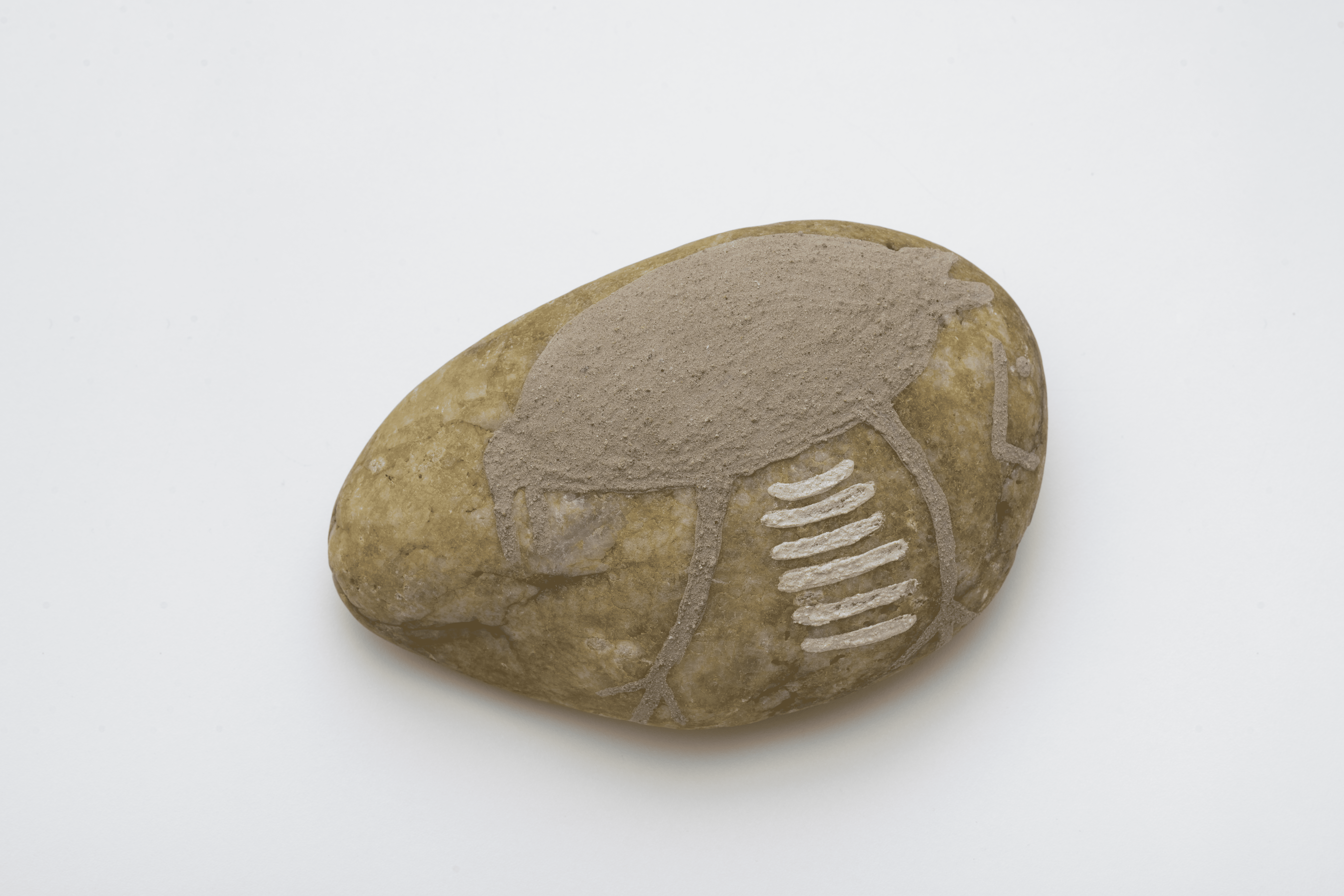 Descrição da imagem: Desenho sobre uma pedra. A pedra é ovalada com uma coloração mesclada em bege e laranja-claro. Uma ave marrom-clara é vista de perfil esquerdo. A cabeça é pequena, o corpo ovalado, o bico curvado para baixo e está aberto. As patas são longas e finas, com três dedos finos e espaçados, e o rabo é curto, com duas pontas arredondadas. Entre as patas, há seis linhas horizontais paralelas, pequenas, finas e brancas. Fim da descrição da imagem.
